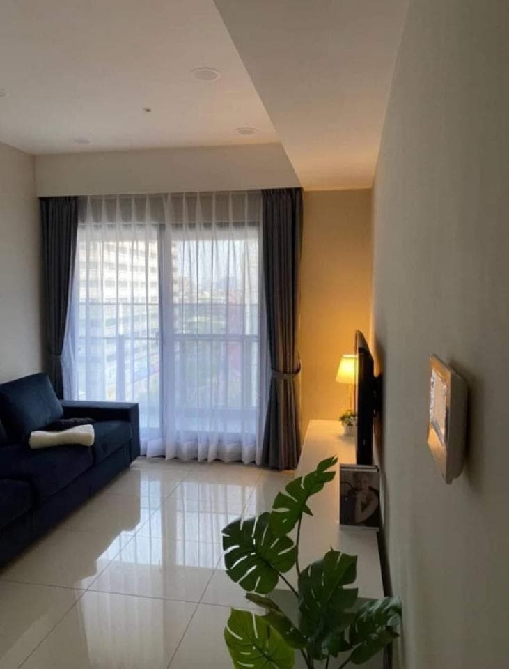 1) 照片顯示一個現代客廳的室內設計,有沙發、窗簾、電視和一盆植物