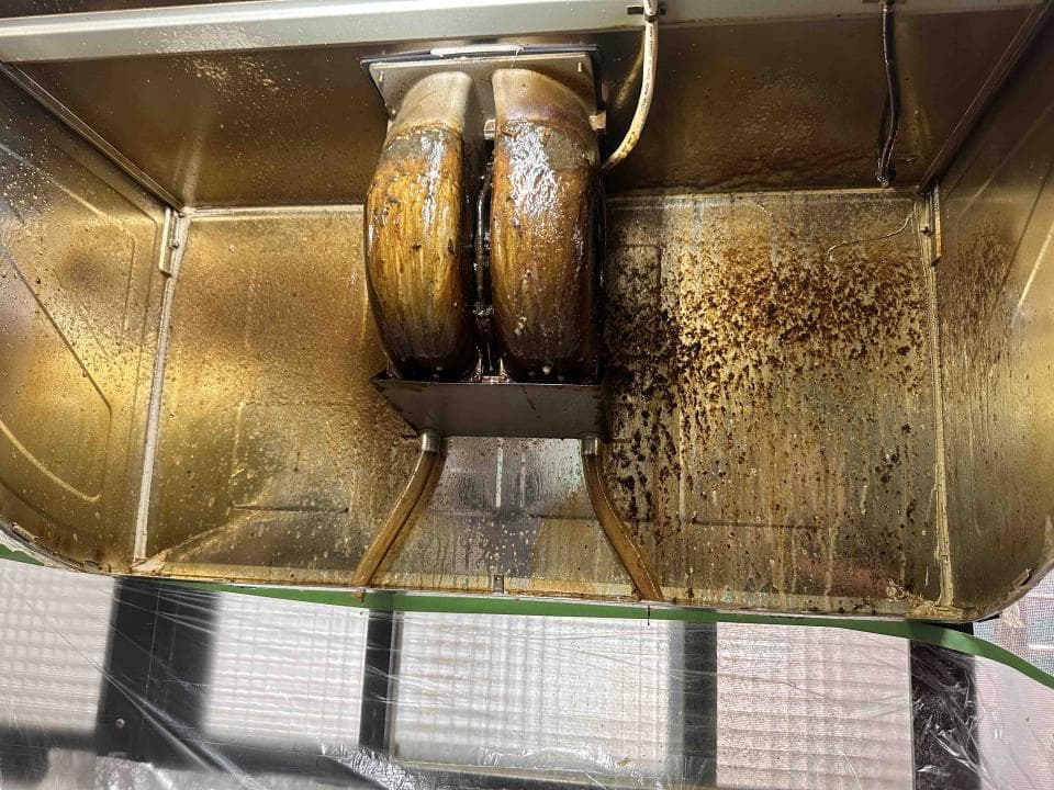 這張照片是一個需要清潔的抽油煙機,它覆蓋著油膩的污垢和油漬。