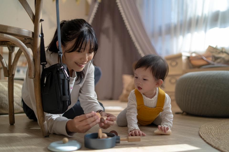 這張「母女玩耍」的照片是一個媽媽和她的寶寶在玩耍,媽媽正在給寶寶玩玩具。