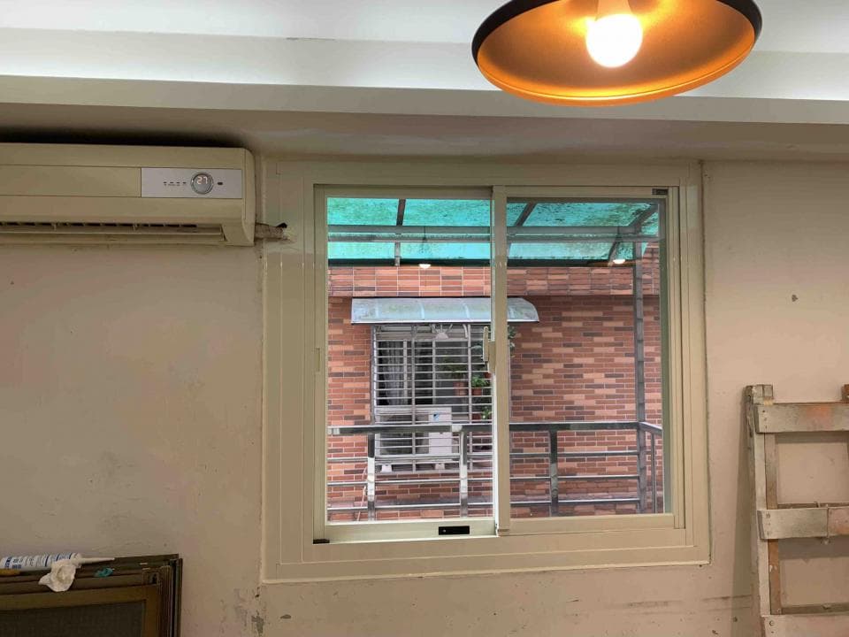 這張照片是一間房間的窗戶,窗戶外可以看見紅磚牆的建築物。