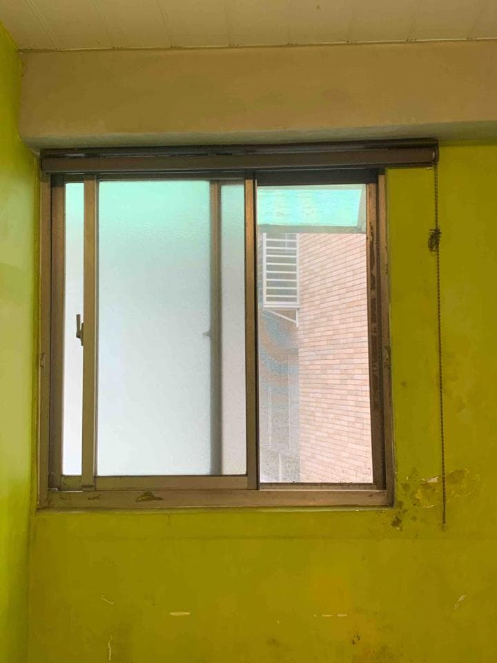 這張照片是一扇窗戶,窗戶外是磚牆,窗戶內有紗窗。