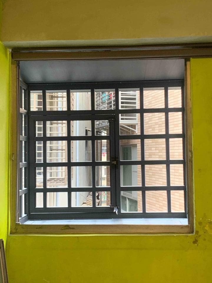 1. 照片中顯示一扇裝有鐵窗的窗戶,窗戶為灰色的,窗戶外牆為黃色