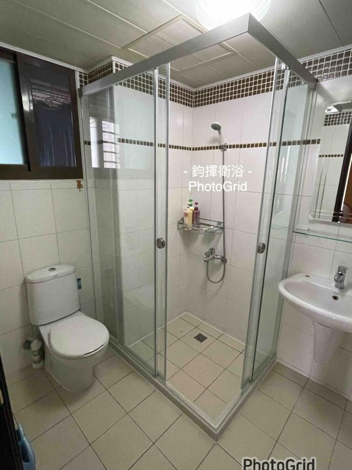 這張照片是一間浴室,最重要的是一個有玻璃門的淋浴間,它位於浴室的右側,是一個方形的空間,內部有淋浴頭、置物架和瓷磚地板。