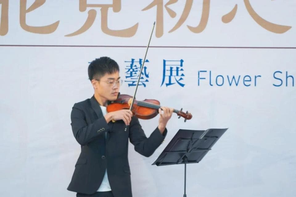 這張照片是一位年輕男子在舞台上演奏小提琴,他專注地演奏,神情投入。