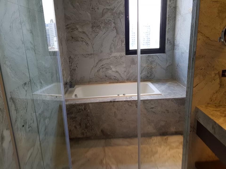 1) 照片顯示一個白色浴缸,位於一個帶有灰色瓷磚的浴室裡