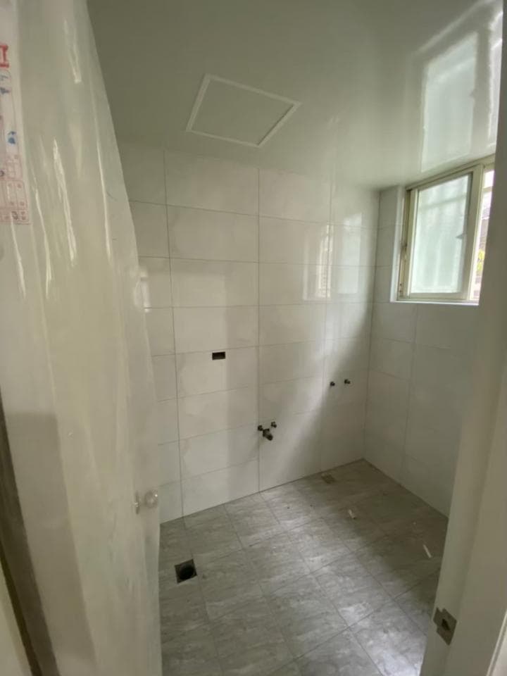 1) 這張照片顯示一個空的浴室,牆壁和地板都鋪上了白色瓷磚