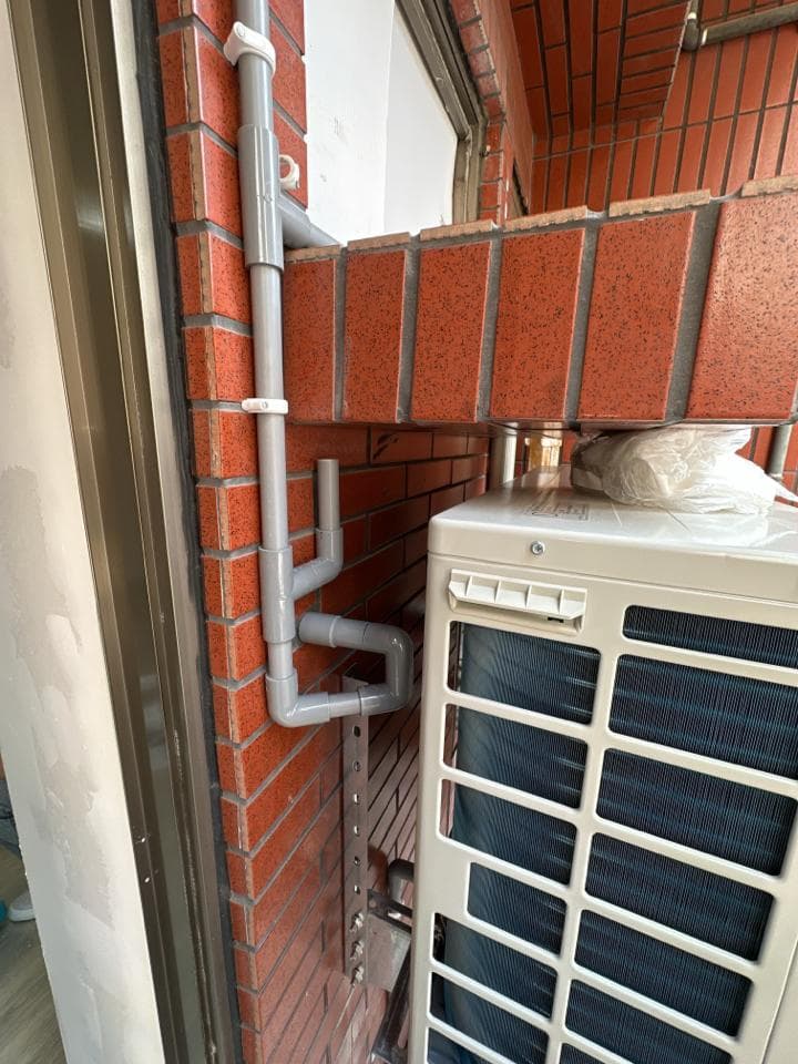 1) 這張照片顯示了室外機安裝在磚牆上,室外機下方是水管和排水管