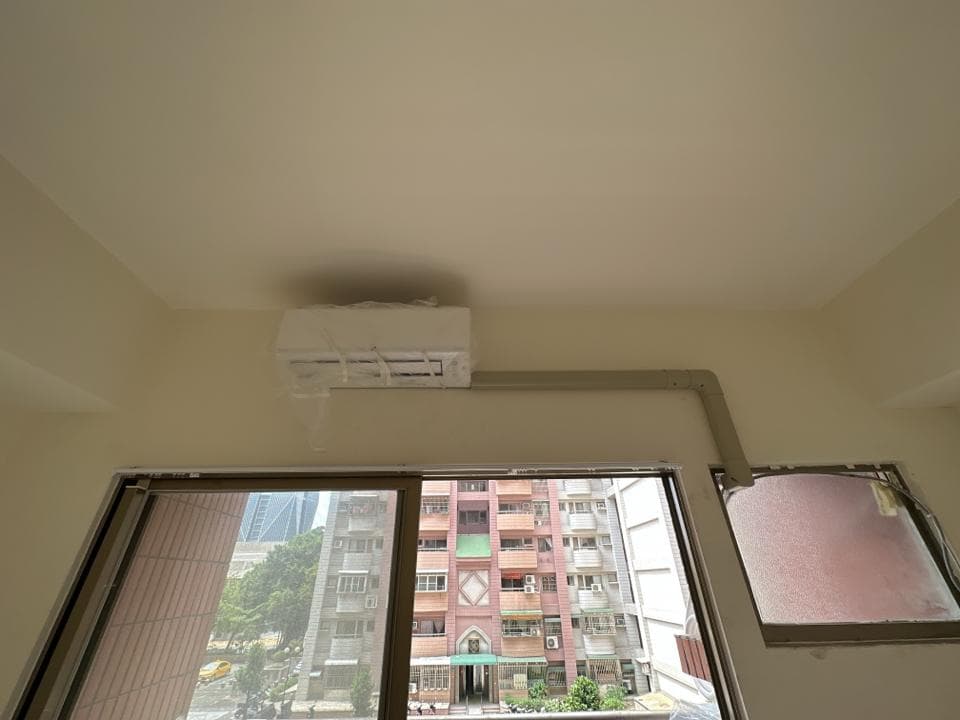 1) 照片顯示一個室內空間,其中有一個白色空調裝置安裝在牆上,並有管線連接