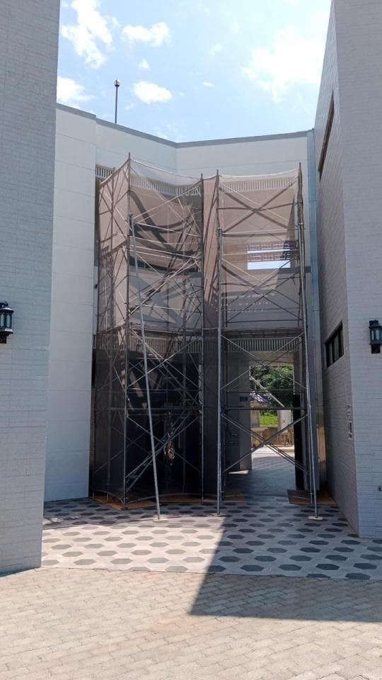 這張「建築工地」的照片是兩棟建築物之間的空間,空間中有兩個大型的鷹架,鷹架上覆蓋著白色網狀材料。