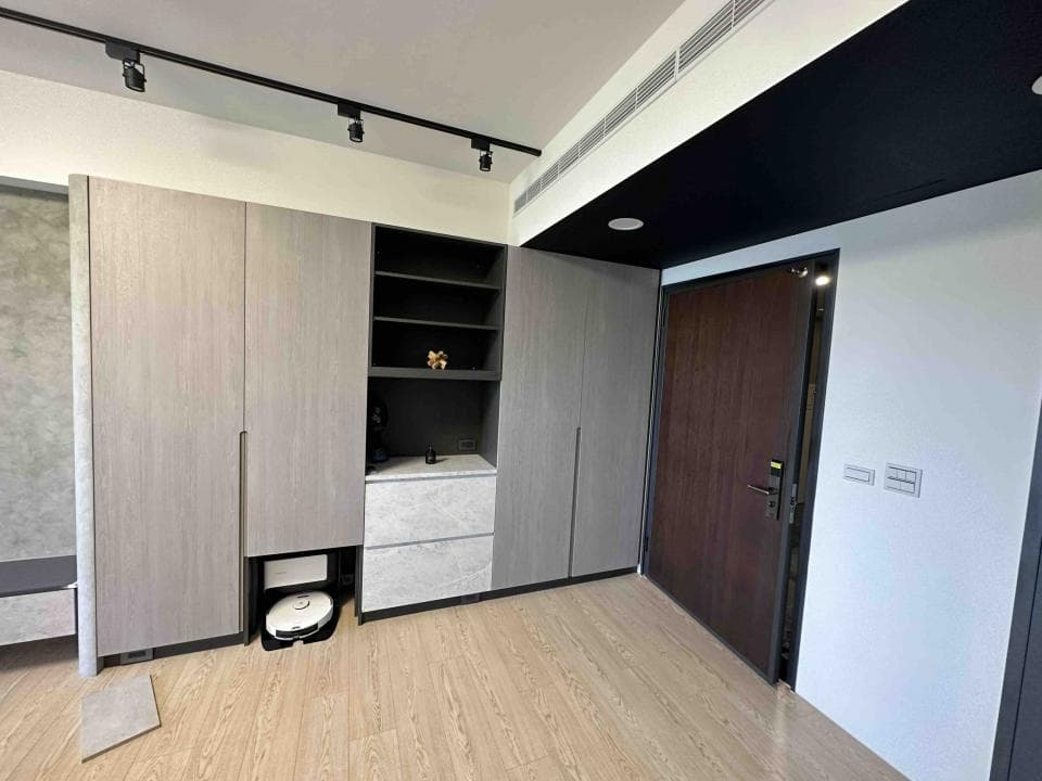 這張照片是一個現代化的客廳,重點是木紋色的牆壁和深色木紋的門,帶給空間一種沉穩又時尚的質感。