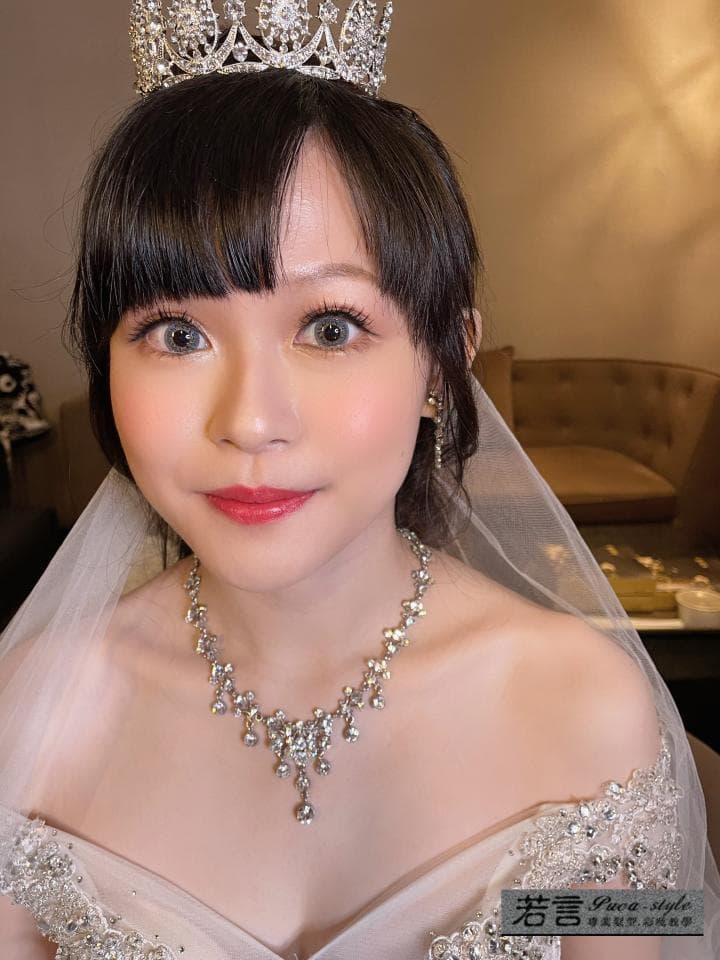 這張婚紗照是一個新娘戴著閃亮皇冠,穿著白色婚紗,並配戴著精緻的項鍊。