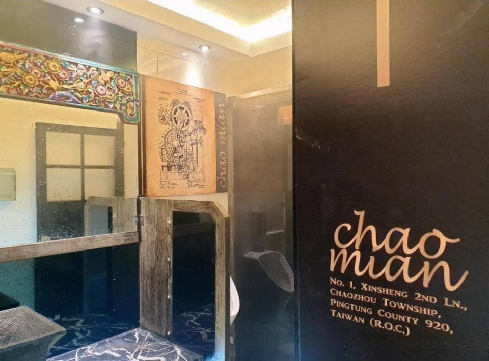 這張「餐廳」的照片是店內的一角,可以看到牆上掛著一幅畫,以及一塊寫著「chao mian」的招牌。牆上的畫看起來像是機械或工程方面的圖。