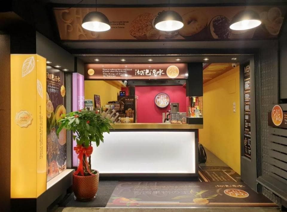 這張照片是一個小吃店,店面非常小,但裝修風格卻很明亮整潔,門口還擺了一盆綠色的盆栽。