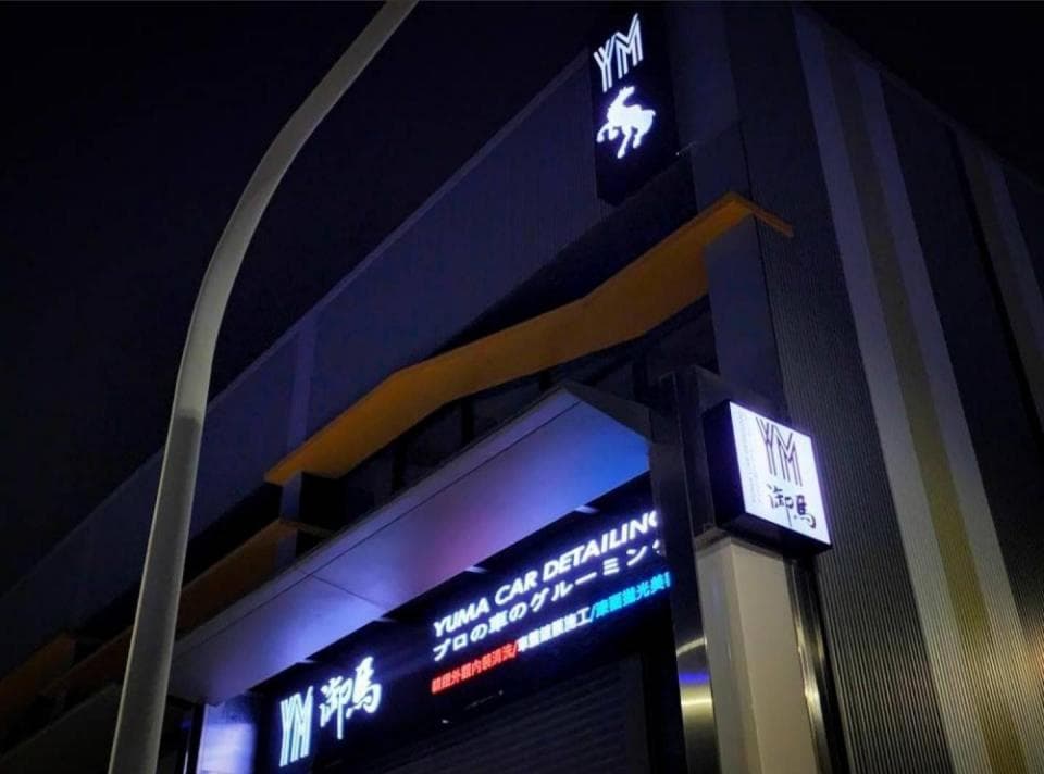 這張「汽車美容店」的照片是,是一家叫做「YM」的汽車美容店,店門口有兩個招牌,上面寫著「YM」和「汽車美容」。