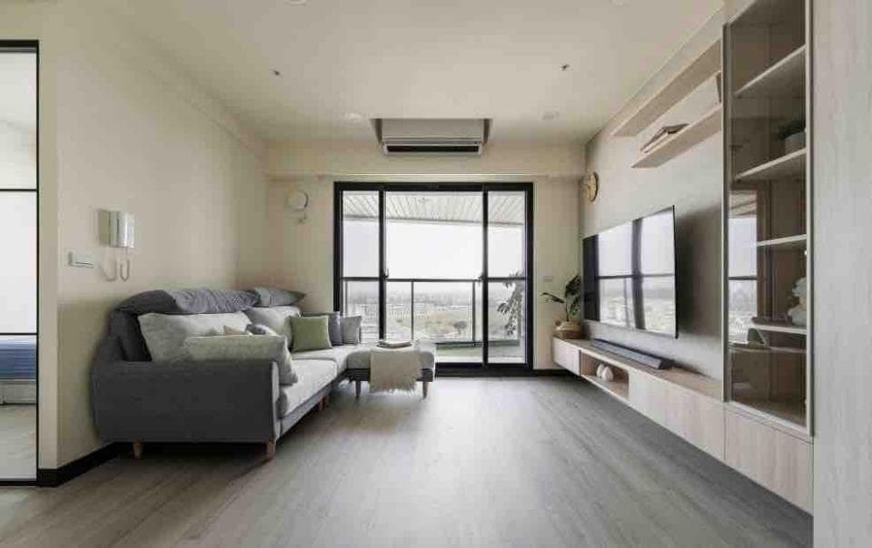這張客廳的照片是一個現代化的空間,有灰色沙發、木質電視櫃,以及落地窗,窗外可以看到城市景觀。