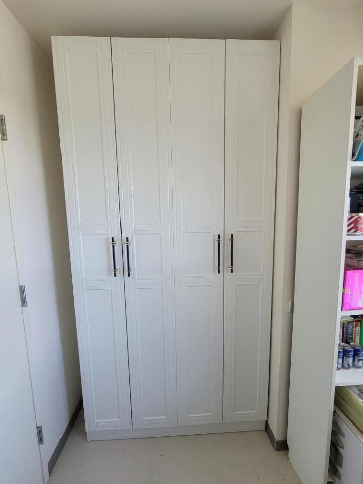 這張照片是一間房間裡的白色衣櫃,有三個櫃門,每個櫃門都有黑色的把手。