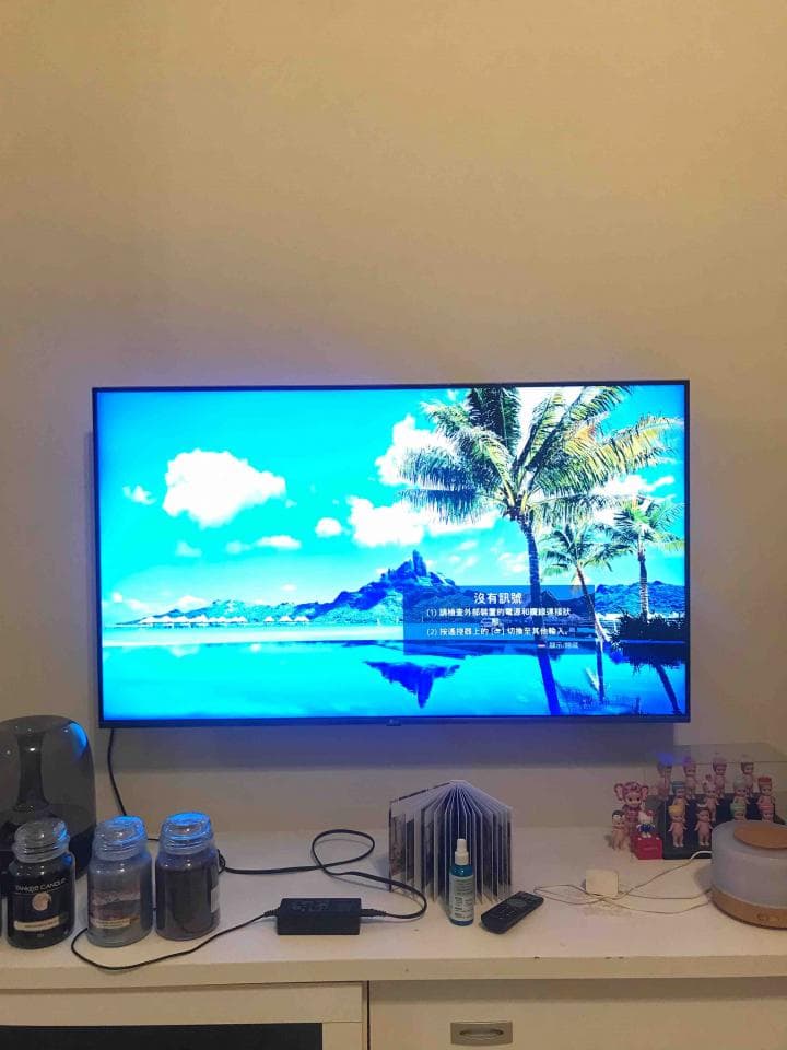 1) 照片中顯示的是一個掛在牆上的電視機,電視機播放的是風景畫,畫面顯示的是沙灘和棕櫚樹