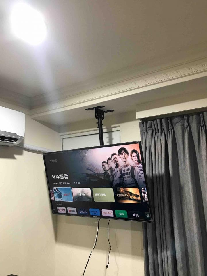 1) 照片顯示一個安裝在牆上的電視,電視螢幕上顯示著一部電影或電視節目