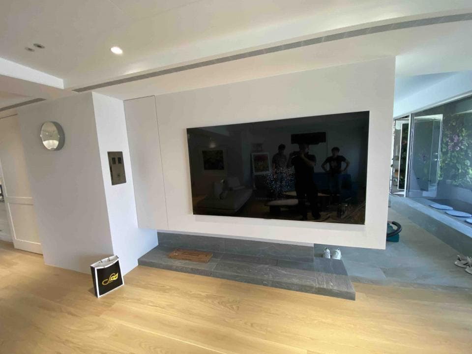 1) 照片顯示一間裝潢精美的客廳,牆上裝飾著一台大型液晶電視,電視下方擺放著木質電視櫃,牆面採用白色,地板為木質地板,室內光線充足