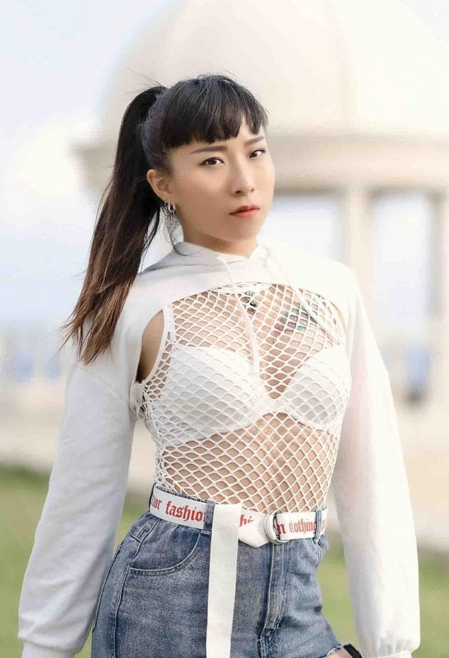 這張「女性時尚」的照片是一名穿著白色網狀上衣,搭配白色腰帶和牛仔短褲的年輕女性。