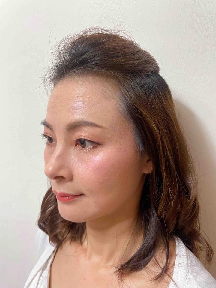 這張「一位女性側臉」的照片是,她擁有深色的長髮,身穿白色上衣,臉上化著淡妝。