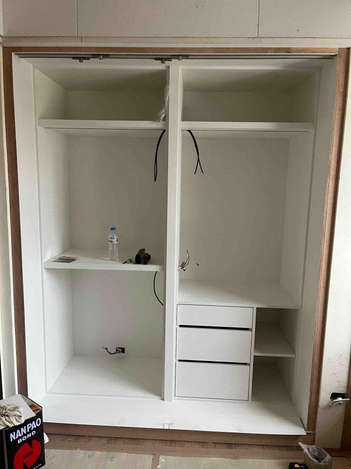 這張照片是一個白色衣櫃,衣櫃有兩個門,裡面有兩層架子和一個三抽屜櫃。