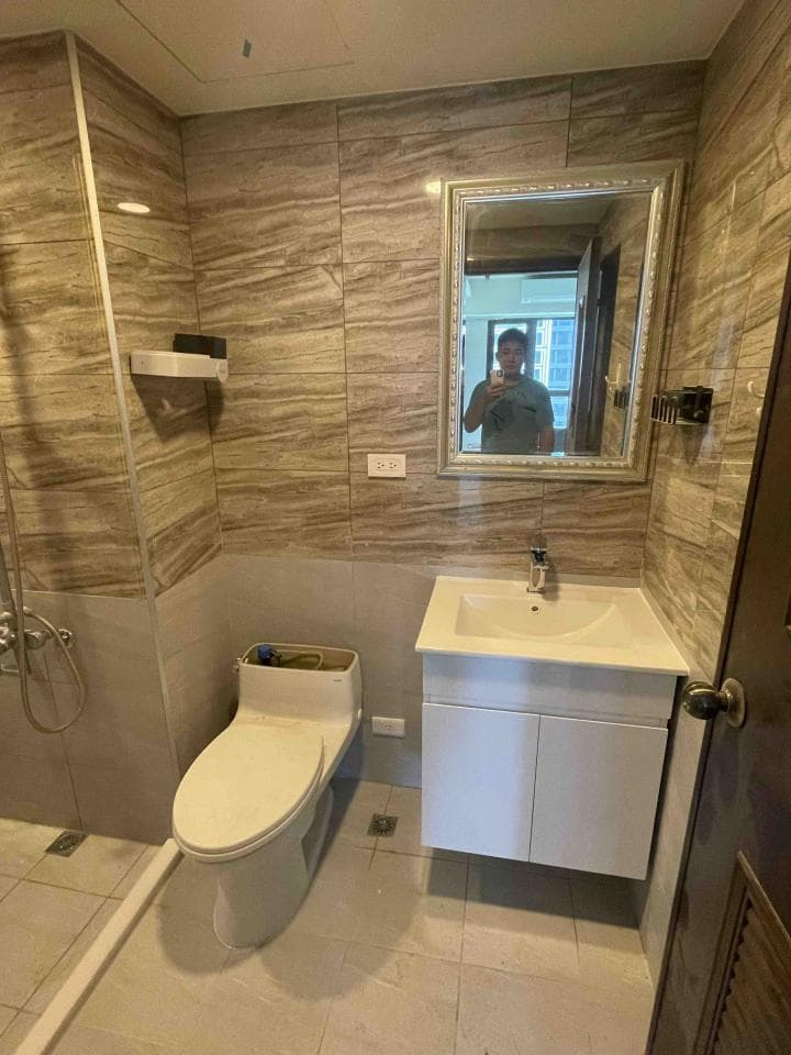 這張照片是一間浴室,最重要的是洗手台和鏡子。鏡子是金色邊框的,洗手台是白色的,下方有一個白色的櫃子。