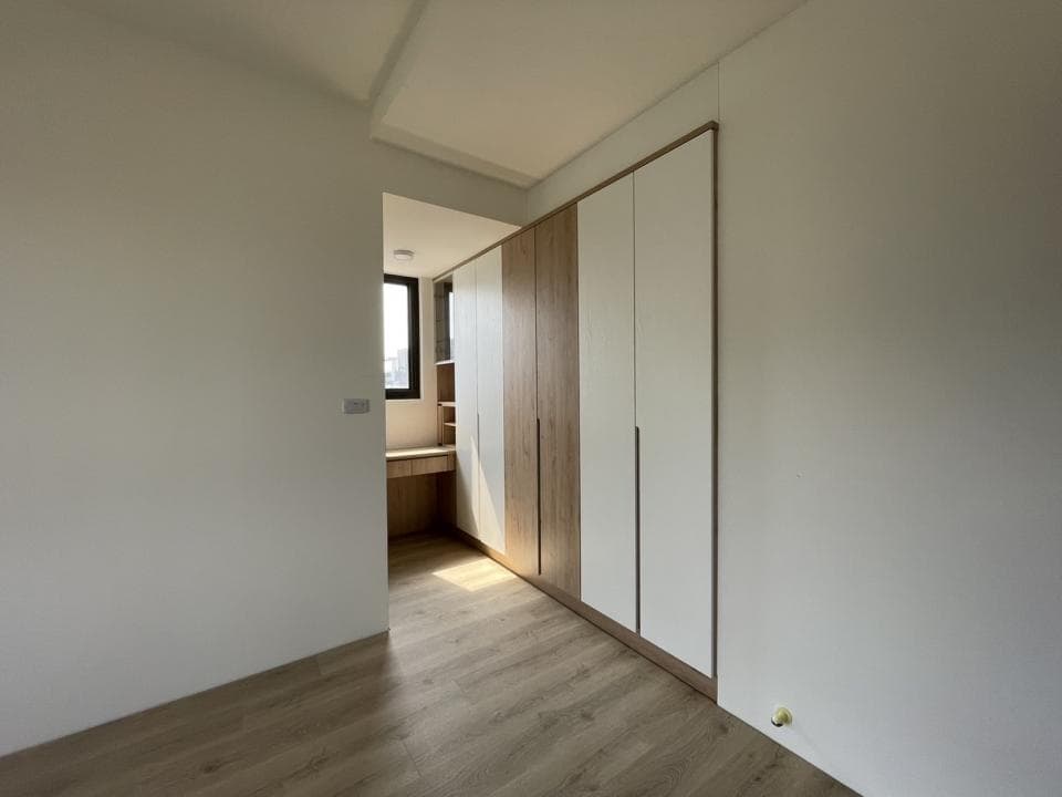 這張照片是一間現代化的臥室,最顯眼的特點是房間內部的嵌入式衣櫃,衣櫃由木質和白色面板組成,呈現簡潔優雅的風格。