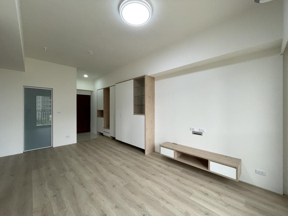 這張照片是明亮簡潔的客廳,牆壁上有一個木質電視櫃,適合放置電視。