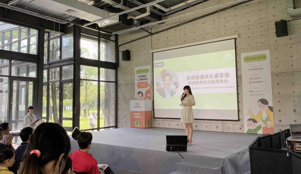 這張「演講」的照片是一個女子在臺上講話,臺下有許多聽眾,背景是一面投影幕,上面顯示著演講主題。