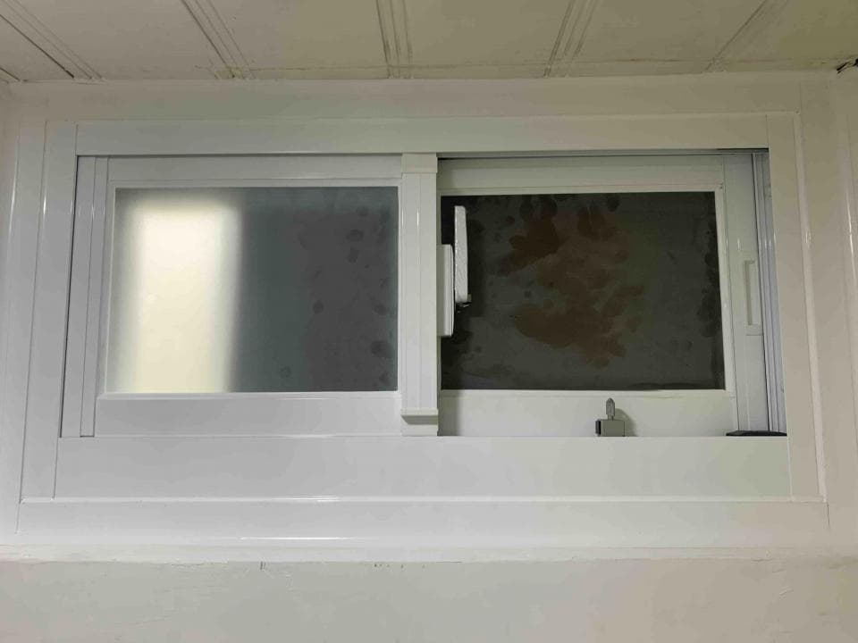 1) 照片顯示一個白色的窗戶,窗戶上有兩扇窗格,其中一扇是霧面的,另一扇是透明的