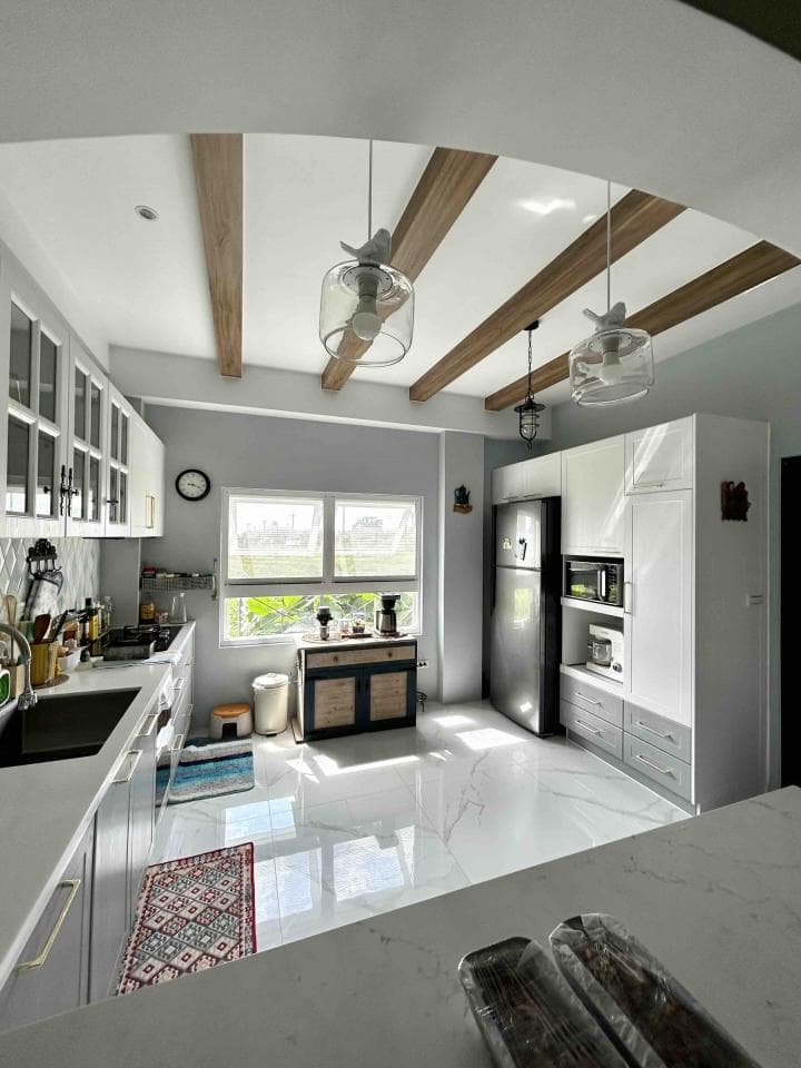 這張照片是現代化的廚房,最引人注目的地方是天花板上的木橫樑,它們以對稱的排列方式創造了視覺上的吸引力,並為空間增添了一份溫馨感。
