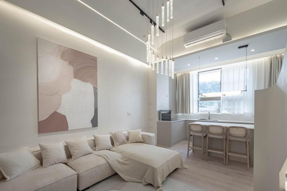 這張「簡約現代客廳」的照片是一間以白色和米色為主的客廳,客廳裡有一張白色沙發和一張抽象畫,客廳的窗戶很大,採光很好,客廳的旁邊還有一個廚房。