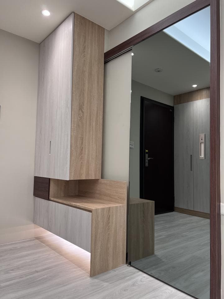 這張照片是一個現代化的玄關,最重要的是木質鞋櫃。鞋櫃由淺色木板和深色木板組成,並配有隱藏式燈光,營造出溫馨舒適的氛圍。