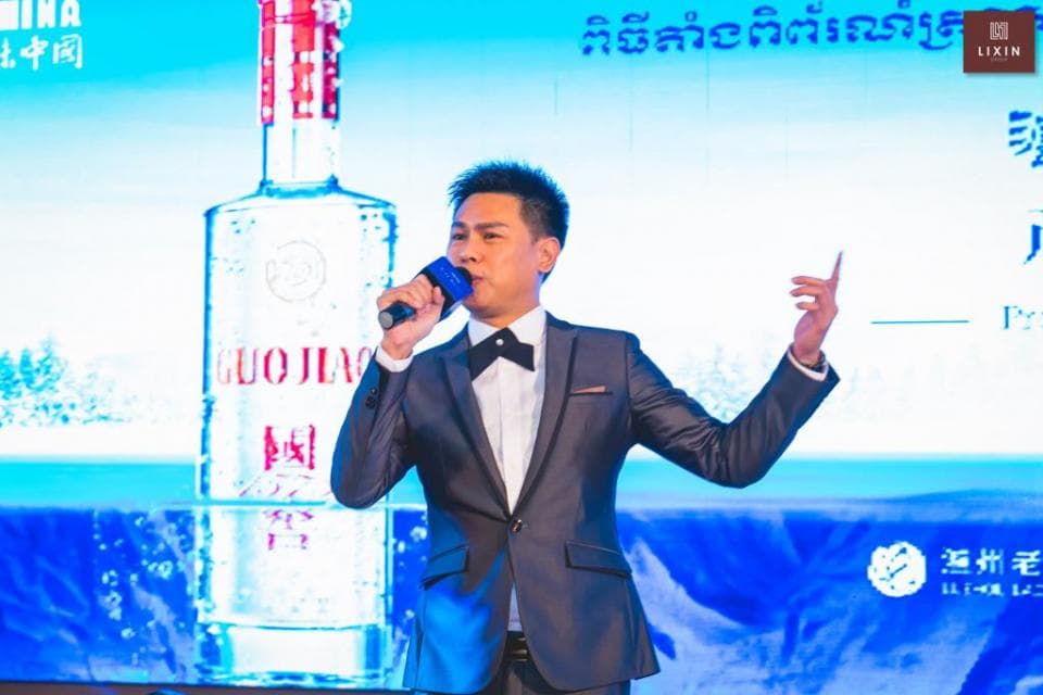 這張「酒類產品發佈會」的照片是,一位身穿西裝的男士正在臺上講話,他的身後是產品的廣告牌,畫面中有一瓶酒,上面印有「國窖」兩個字。