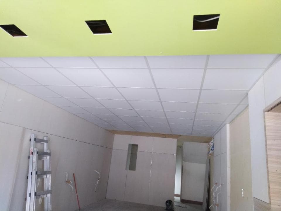 1) 照片顯示一個正在裝修的房間,房間的天花板裝有白色的天花板,牆壁大部分都是白色的,房間裡有一把梯子,以及一些裝修的工具