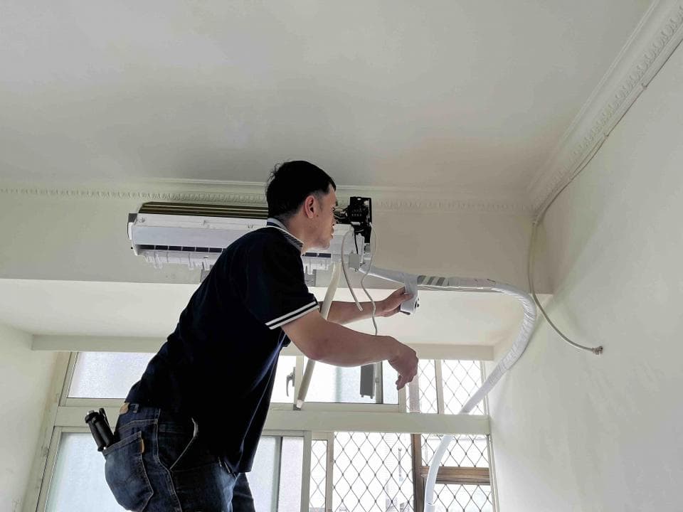 這張照片是一個修理冷氣的技術人員,他正在檢查冷氣的管線,並調整冷氣的設定。