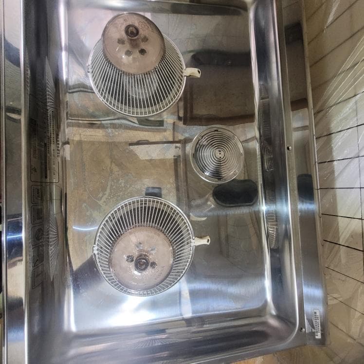 這張照片是一個不銹鋼的爐灶,上面有三個燃燒器,每個燃燒器都有一个金屬網蓋。