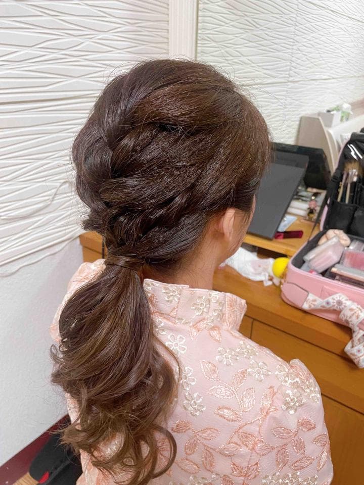 這張照片是一個年輕女性,她留著一頭漂亮的棕色長髮,編成了精緻的髮型,髮尾綁成馬尾,散落在肩上,展現出優雅的氣質。