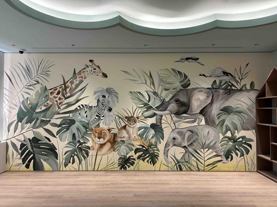 這張「動物主題」的照片是,牆上畫滿了熱帶叢林,有長頸鹿、斑馬、獅子、大象和一隻小象。