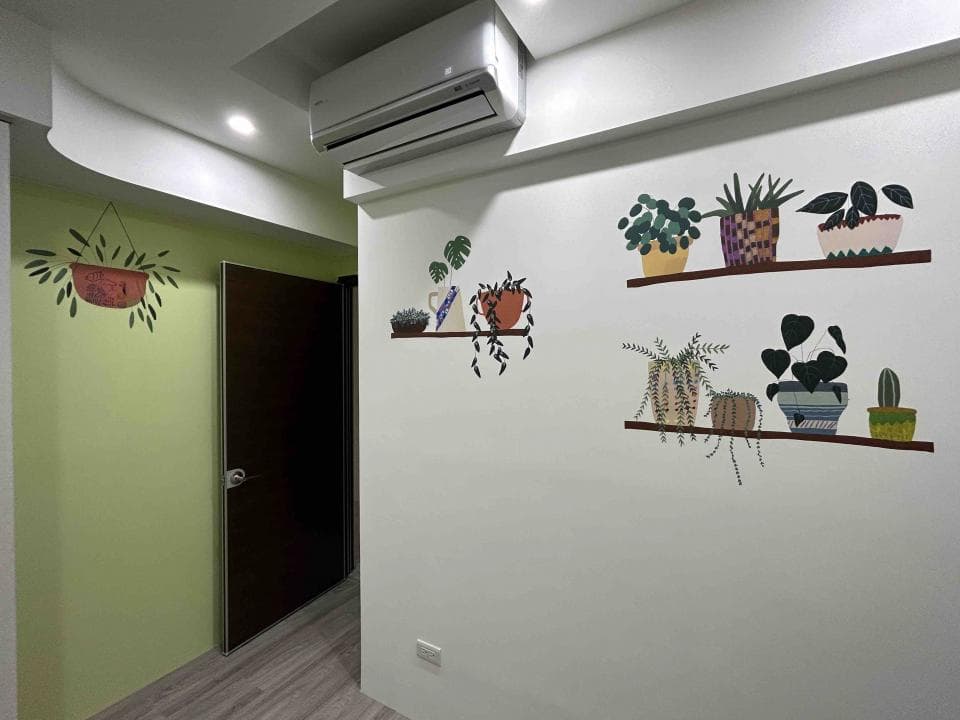 這張「室內」的照片是牆壁上畫了很多盆栽,旁邊有一扇木門,地板是木地板。