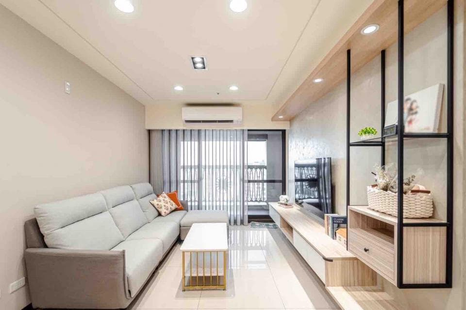 1) 這張照片顯示一個現代化的客廳,配有灰色沙發、木質地板、木質電視櫃和黑色金屬架子,架子上擺放著裝飾品和書籍