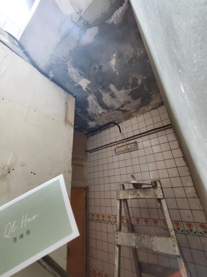1) 照片顯示一個正在裝修中的浴室,浴室天花板有損壞,牆壁上裝有瓷磚,地上放著一個梯子