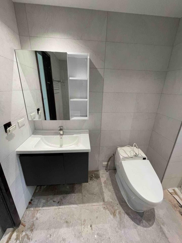 這張照片是一個現代化的浴室,最重要的部分是馬桶。馬桶是白色,安裝在左邊牆壁,看起來很新,而且有智能馬桶蓋。