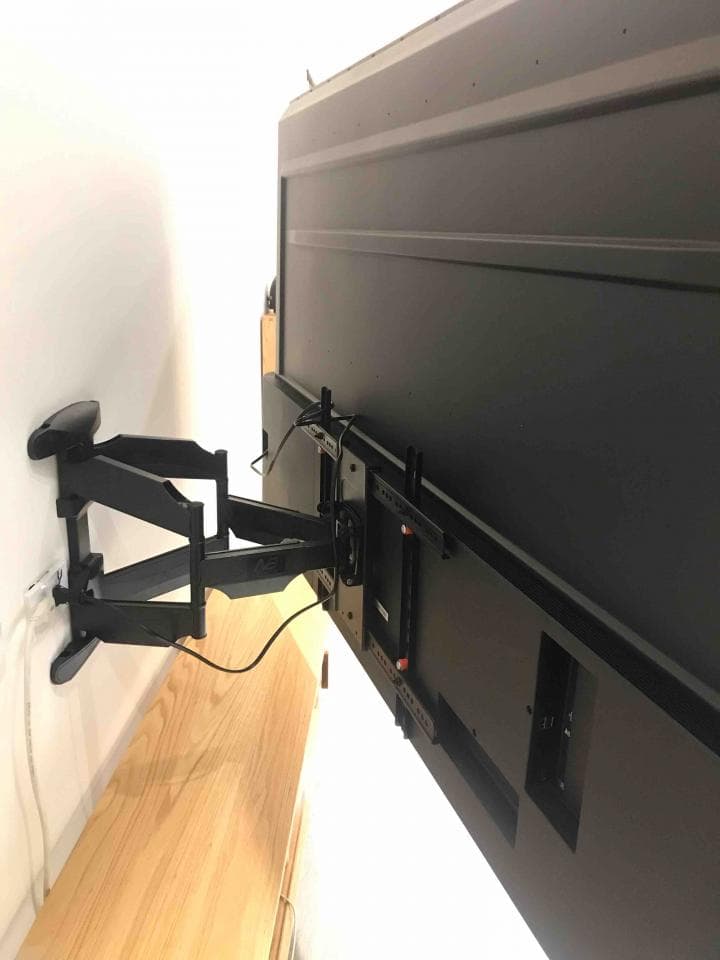 這張照片是一個電視牆,電視用黑色壁掛架固定在牆上。