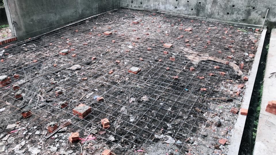 1) 照片顯示一個水泥地面,上面鋪設了金屬網格,一些紅磚散落在地面上