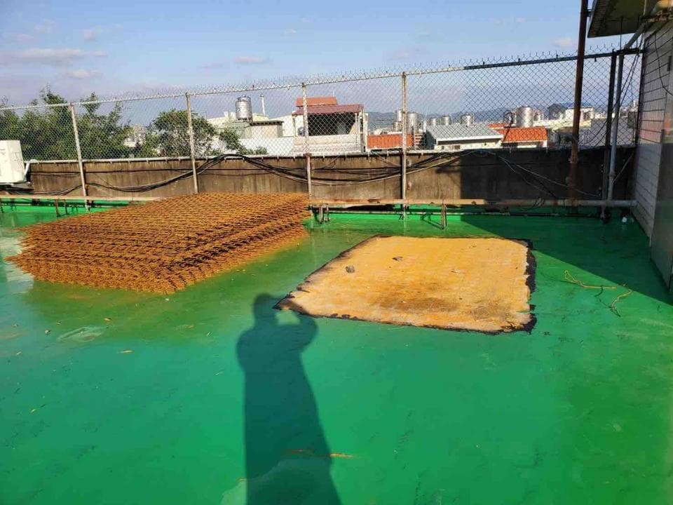 1) 照片顯示一個綠色的屋頂,屋頂上放著一塊生鏽的鐵網