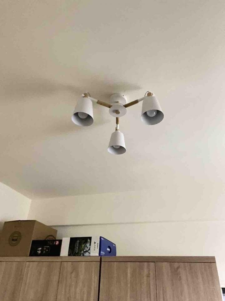 1) 照片顯示一個現代的木質燈具,有三盞白色燈罩,裝在天花板上的木質櫃子上方