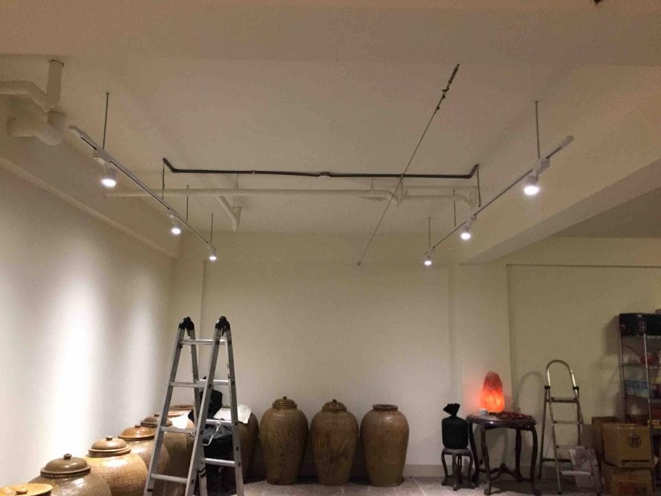 1) 這張照片顯示一個房間的內部,裡面有幾個陶罐、一個梯子、一個燈、一個小桌子和一張椅子