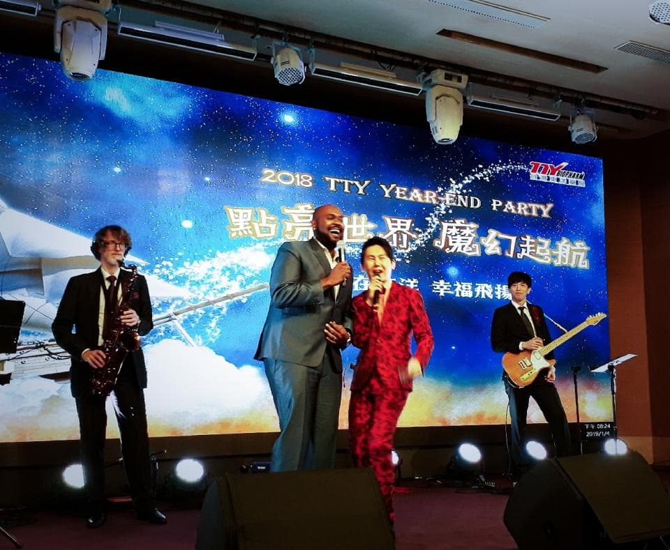 這張「2018 年終派對」的照片是四個人在臺上唱歌和演奏音樂。